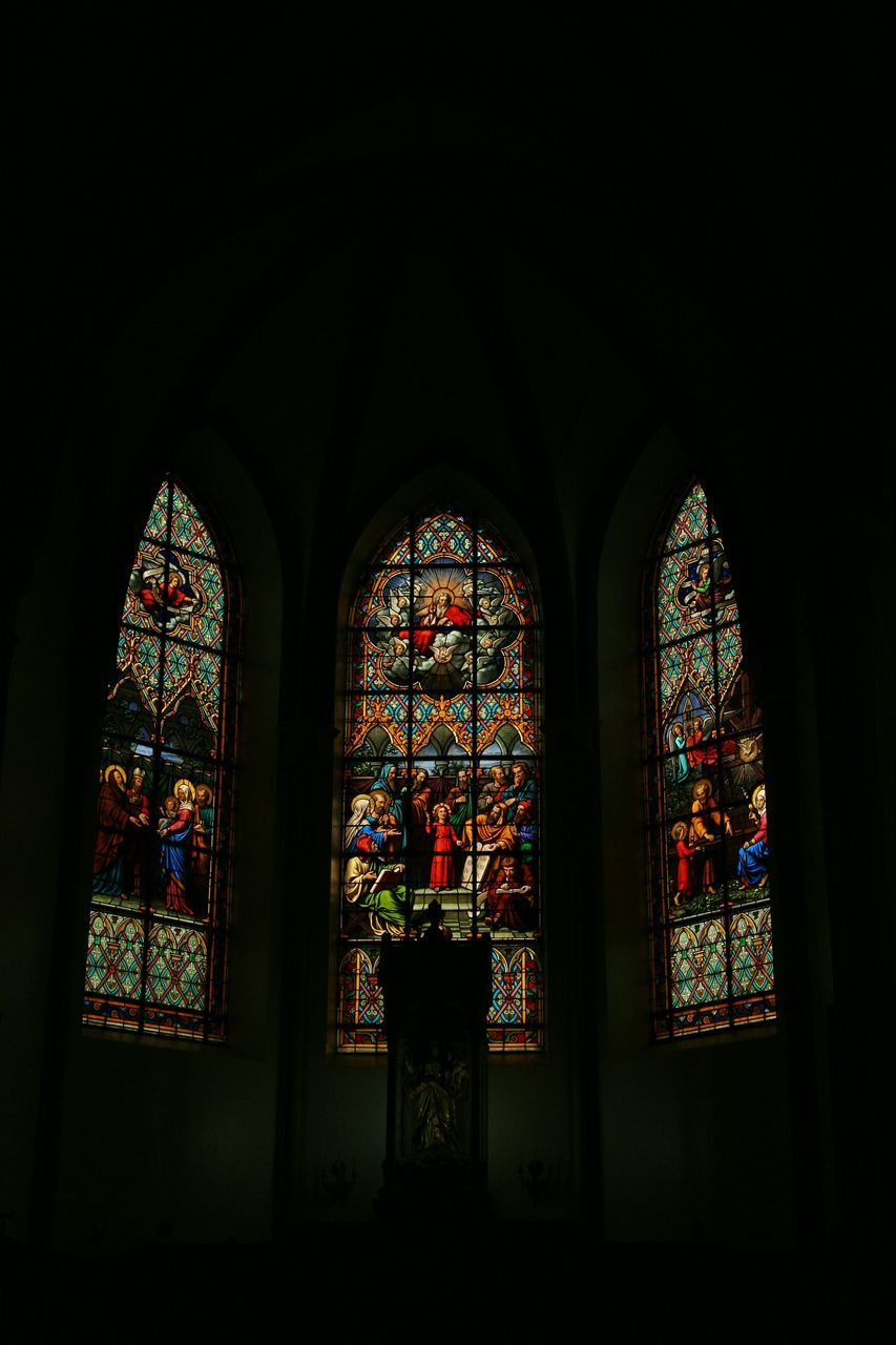 place of worship, religion, indoors, spirituality, church, arch, window, architecture, built structure, stained glass, low angle view, human representation, art, temple - building, ornate, cathedral, dark, illuminated