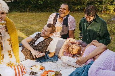 Friends of lgbtq community enjoying fruits and drinks lying in back yard