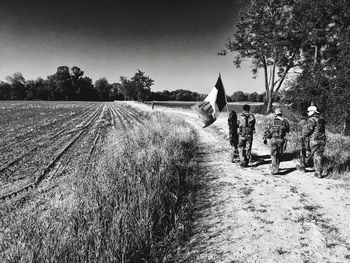 People on agricultural field against sky