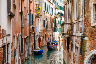 Tourists sailing in a gondola on the beautiful canals of venice in an early spring day