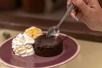 Hand holding ice cream cone on table