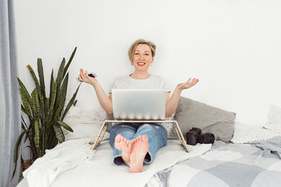 Portrait of young woman sitting on bed at home