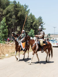 People riding horse cart against trees