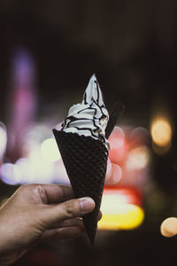 Close-up of hand holding ice cream cone against blurred background