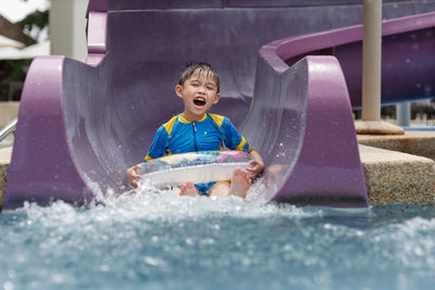 Boy sliding down in water slide at water park