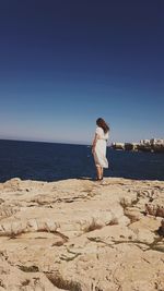 Woman standing at beach against sky