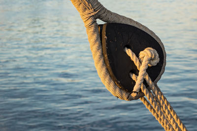Close-up of rope tied on pulley against sea