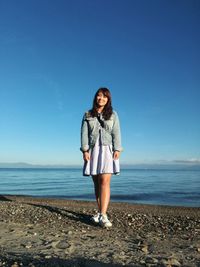 Full length of woman standing at beach against clear sky