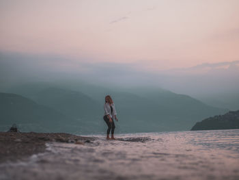 Woman standing on mountain against sky during sunset