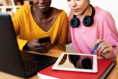 Midsection of lesbian couple using wireless technology at home