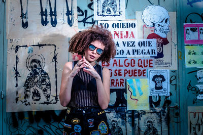 Woman standing against graffiti wall