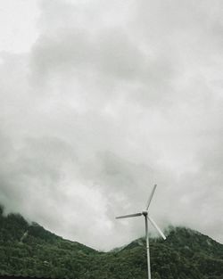 Low angle view of windmills on landscape against sky