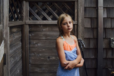 Portrait of girl with towel standing against log cabin