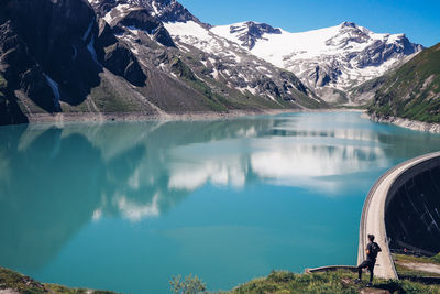 Scenic view of lake by snowcapped mountains against sky