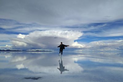 Rear view of man standing in lake against sky