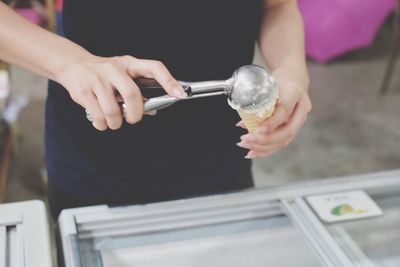 Midsection of woman scooping ice cream in cone