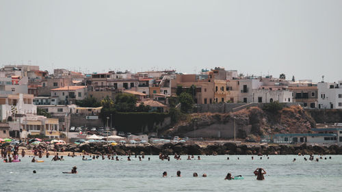 Coastal view from the mediterranean sea in sicily. there is a beach and people in the water.