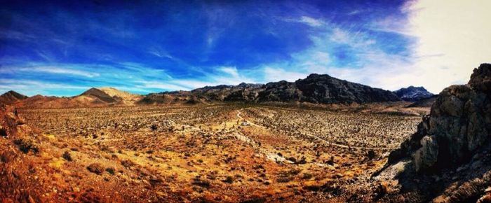 Scenic view of desert land against blue sky