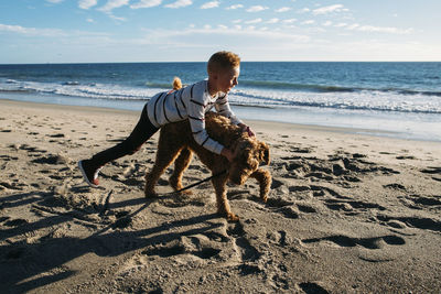 Boy playing with dog at beach