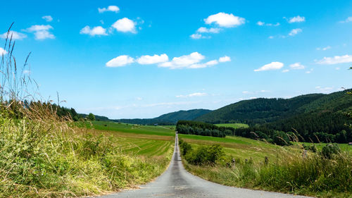 Empty road along countryside landscape