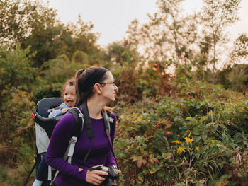 Smiling mother with cute son on back standing on forest