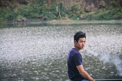 Side view of young man looking away in lake