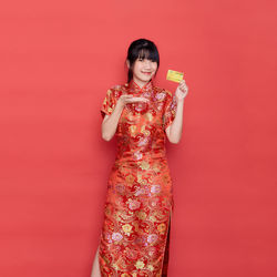Portrait of a smiling young woman against red background