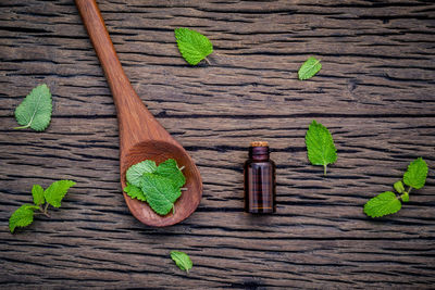 Directly above shot of bottle with herbs on wooden table