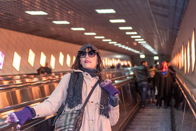 Woman in warm clothing standing on escalator