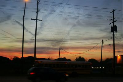 Cars on illuminated bridge against sky during sunset