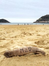 Text on sand at beach against sky