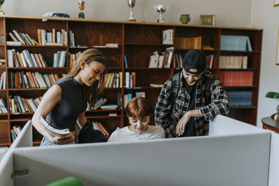 Male and female students against bookshelf in library