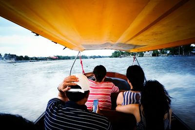 Rear view of people on speed boat at lake