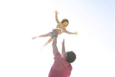 Playful father having fun with daughter under clear sky on sunny day