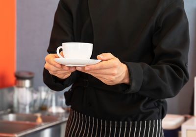 Midsection of man holding coffee cup