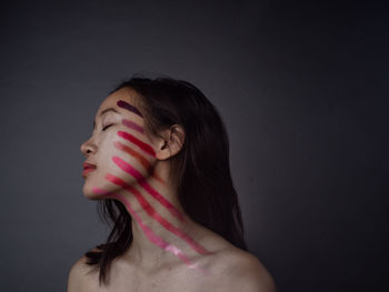 Young woman with eyes closed against black background