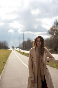 Young woman standing on road against sky