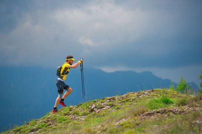 Man climbing on mountain against sky