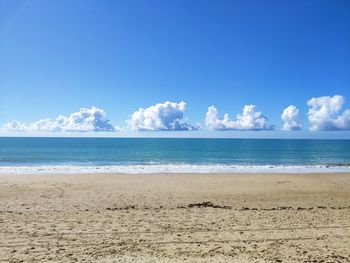 Scenic view of beach against blue sky