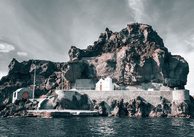 View of rock formations by sea against sky