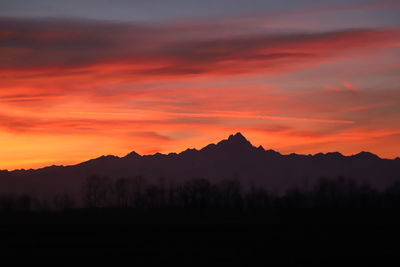 Scenic view of silhouette mountains against orange sky