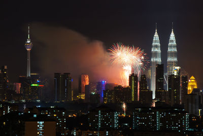 Firework display by petronas towers and buildings in city