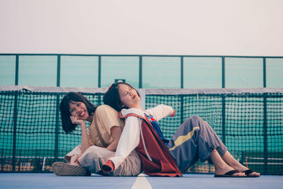 Friends sitting on railing against sea