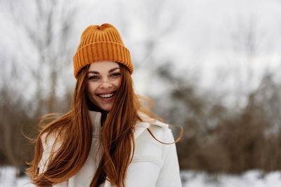 Portrait of young woman standing against trees during winter