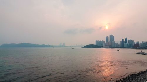 Scenic view of sea and buildings against sky during sunset