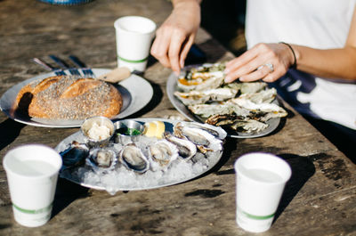 Midsection of woman having oysters on table