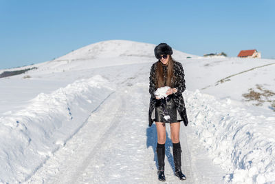 Full length of woman standing on snow against sky