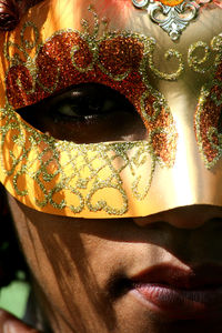 Close-up portrait of woman wearing orange carnival mask