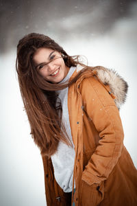 Portrait of young woman standing against wall