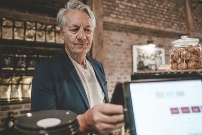 Senior businessman paying through smart phone at cafe counter